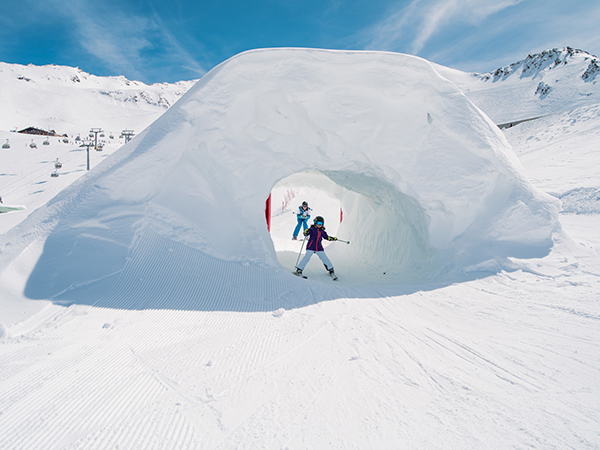 child skiing through snow tunnel